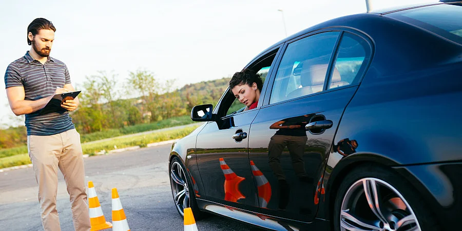 Fahrlehrer bewertet Fahrschülerin während der Fahrprüfung im Auto