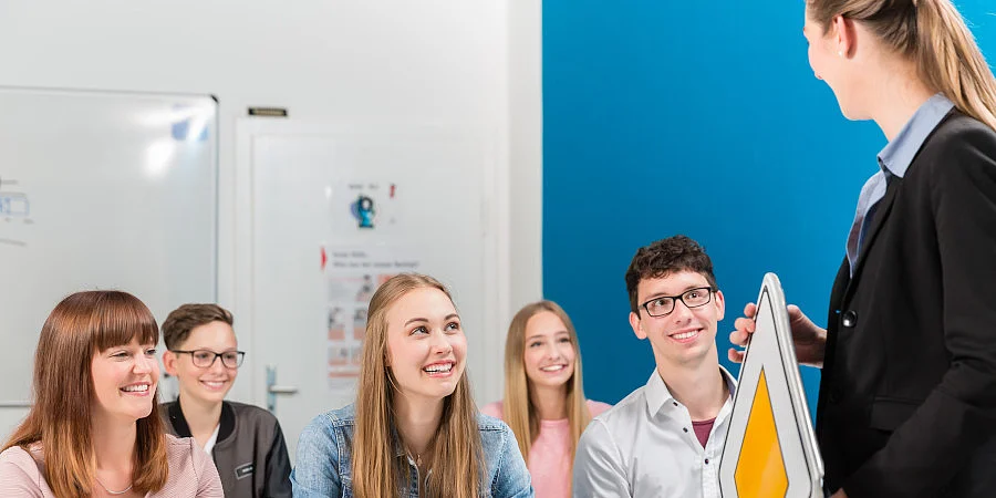 Lehrerin zeigt Verkehrszeichen einer Gruppe junger Schüler.